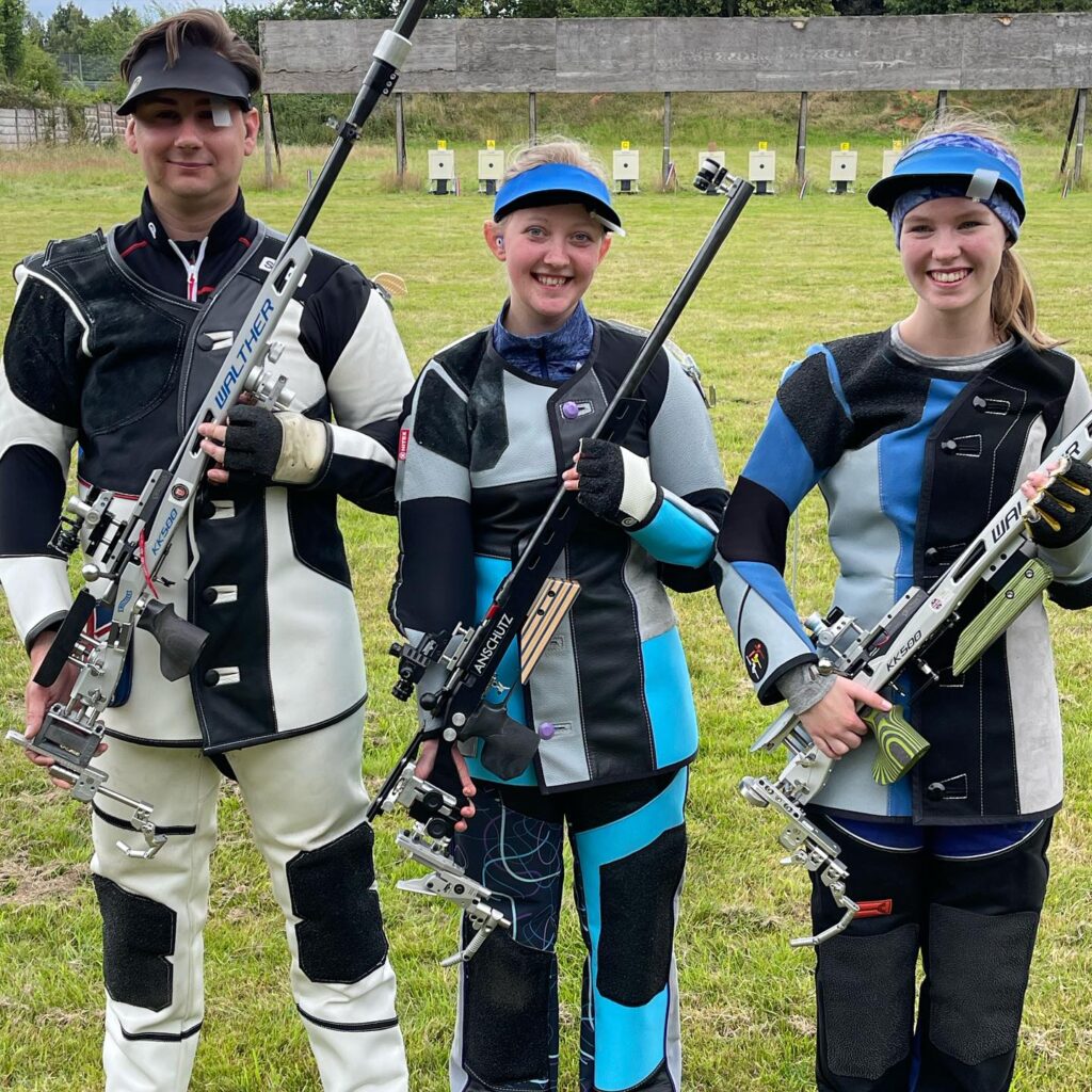 Three rifle shooters holding their rifles and smiling. They are the medallists from the July edition of British Shooting's 50Metre Rifle Series.
