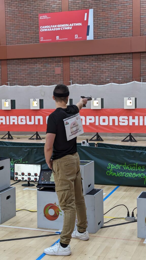 A young man aims an air pistol at a shooting match