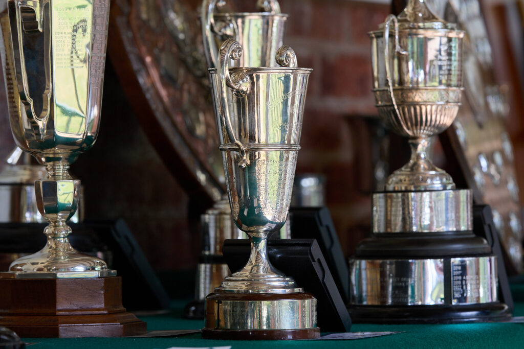 Silver trophies stand on a table awaiting their winners.